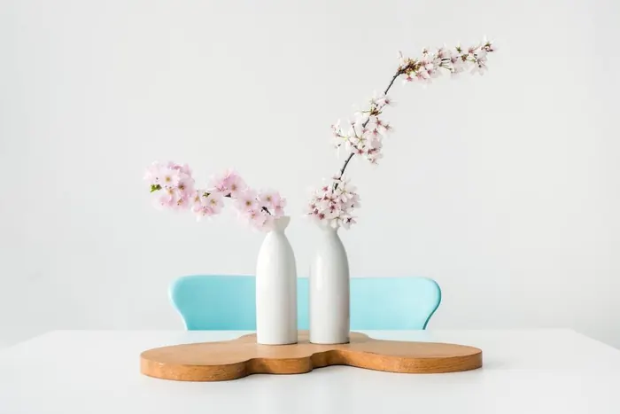 Two small white vases with cherry blossom stems