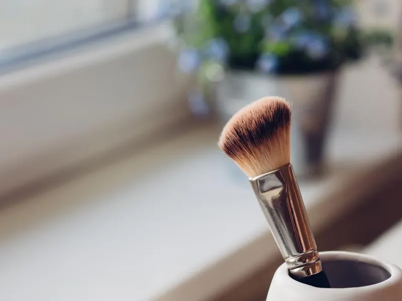 A soft brush in a white cup on a sunny windowsill